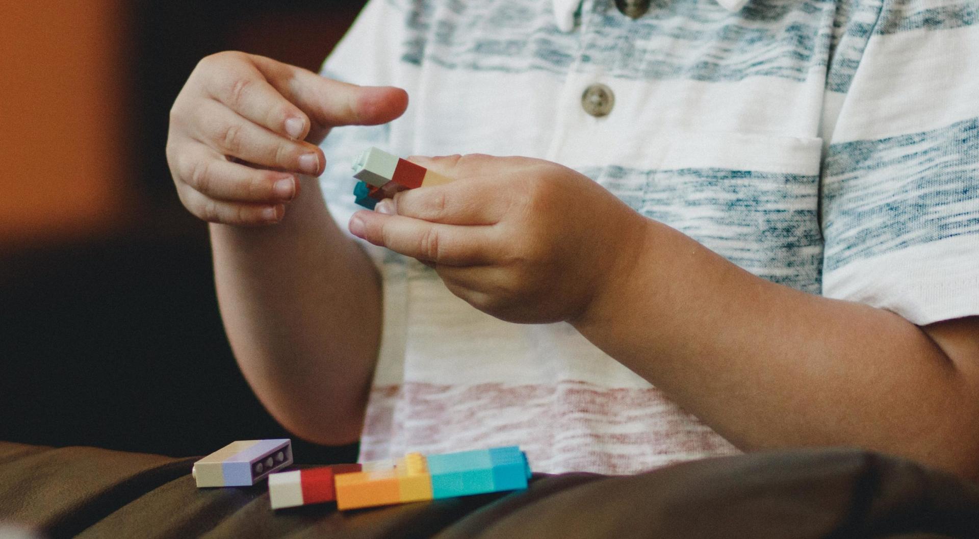 A young child with autism plays with colourful building blocks