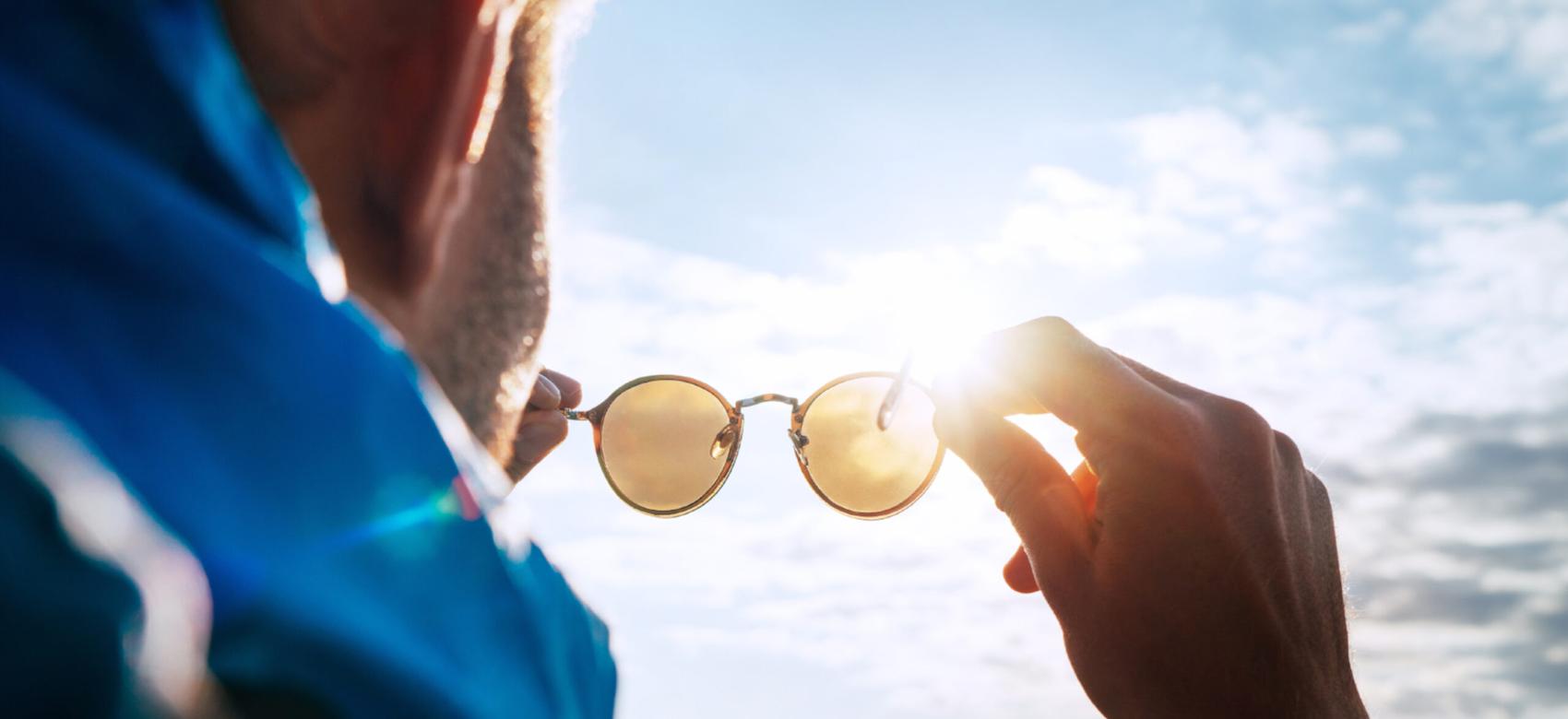 A person looking at the sun through their sunglasses.