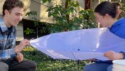 Two students are engaged in fieldwork, collecting samples of insects and microbes for ecological analysis.