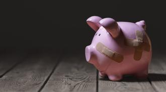 A pink piggy bank with bandaids on dark background
