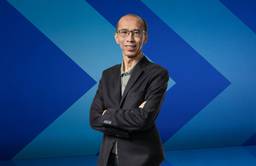 Dr. Raymond Ng stands in front of a blue chevron background.