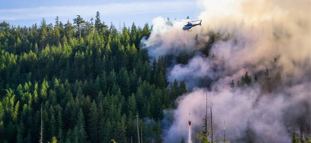 Helicopter fighting British Columbia forest fires during a hot sunny summer day.