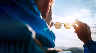 An image of a man looking at the sky through sunglasses.