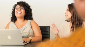 Two women laugh together at an office