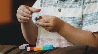 A young child with autism plays with colourful building blocks