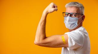 A man posing with his arm up against orange background.