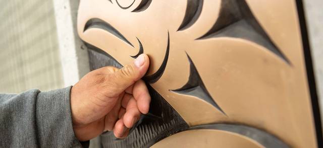 Musqueam artist Brett Sparrow with the bronze cast of his artwork on the UBC Vancouver campus