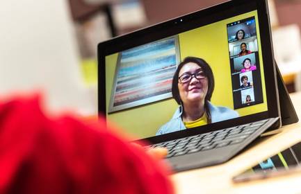 A laptop screen shows a video conference conversation between several seniors