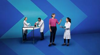 Three people in white lab coats and a person in a pink shirt working in a stylized lab with chevron backdrops.