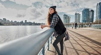 A young woman leaning on a railing next to Vancouver's False Creek