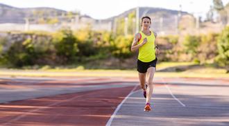 Malindi Elmore in a yellow tank top and black shorts running on a track