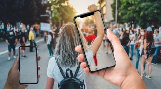 Taking pictures of young woman raising her fist up with phones