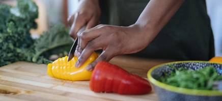 A person cuts up bell peppers for a salad to avoid food waste