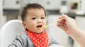 A baby boy eating blend food on a high chair