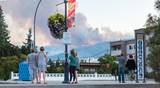 Penticton, BC/Canada - August 29, 2021: Pedestrians watch from Lakeshore Drive as a forest fire flares up in the hills above the city.